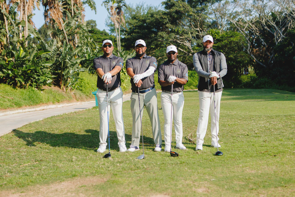Four golfers posing together with their clubs on the course