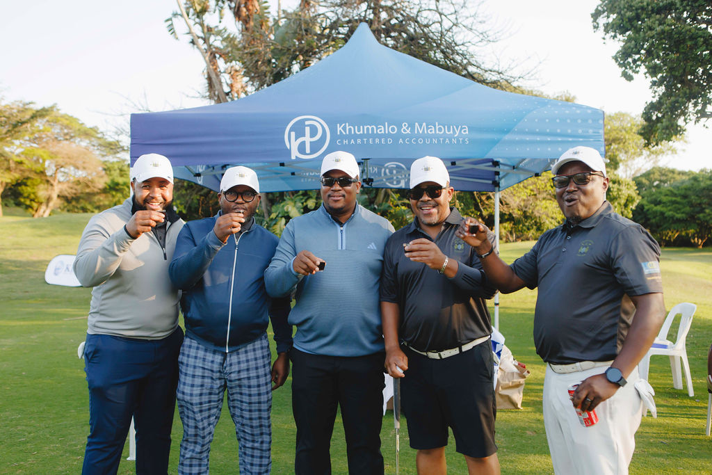Golf day participants posing together beside an event gazebo